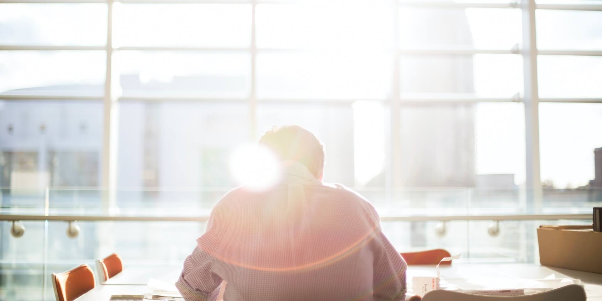 person sitting at a desk with the sun shinning on them